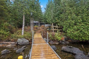 Un ponte di legno conduce a una baita circondata da un bosco fitto.