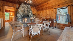 A cozy cabin interior with a stone fireplace, wicker chairs, and wooden walls.