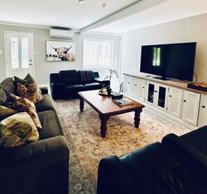 Een woonkamer met een bank, een salontafel, een televisie en een kast.