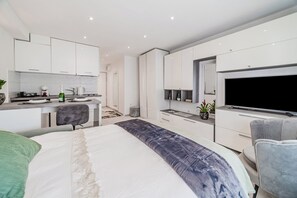 Ein modernes Schlafzimmer mit einem großen Bett, einem Schreibtisch und einem Fernseher.