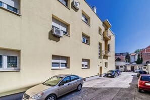A multi-story residential building with air conditioning units, a parking area with several cars, and a clear blue sky. - Zagreb City Center Vibes Near Main Square, Zagreb, Croatia (Zagreb)
