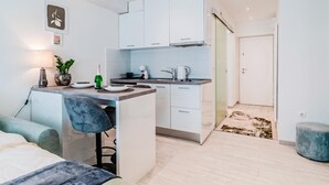 A compact kitchen with white cabinets, a bar area, and a dining space with a chair and table. - Zagreb City Center Vibes Near Main Square, Zagreb, Croatia (Zagreb)