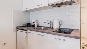 A compact kitchen with white cabinets, a stainless steel sink, and a coffee maker. - Zagreb City Center Vibes Near Main Square, Zagreb, Croatia (Zagreb)