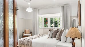 Une chambre à coucher avec un lit, une chaise, une lampe et une fenêtre avec des rideaux.