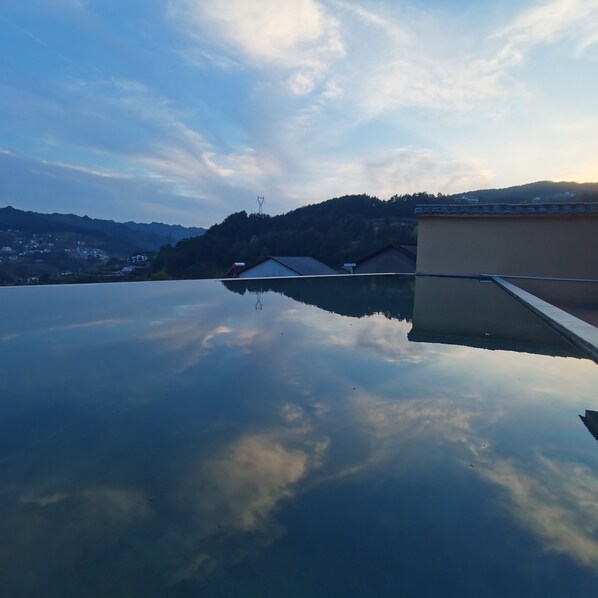 A rooftop with a clear view of the surrounding landscape, including distant hills and a power line tower. - Cloud House Of Leisurely (Zhangjiajie)