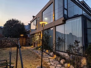 A modern two-story house with large windows, a stone pathway, and outdoor lighting. - Cloud House Of Leisurely (Zhangjiajie)