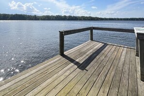 A wooden dock extending into a calm lake with a forested shoreline in the background.