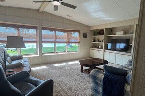 A living room with a sofa, a coffee table, a TV, and a ceiling fan.