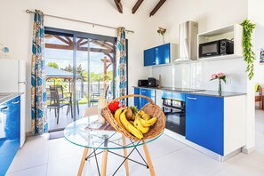 Eine moderne Küche mit blauen Schränken, einem Glastisch und einem Korbkörbchen mit Früchten.