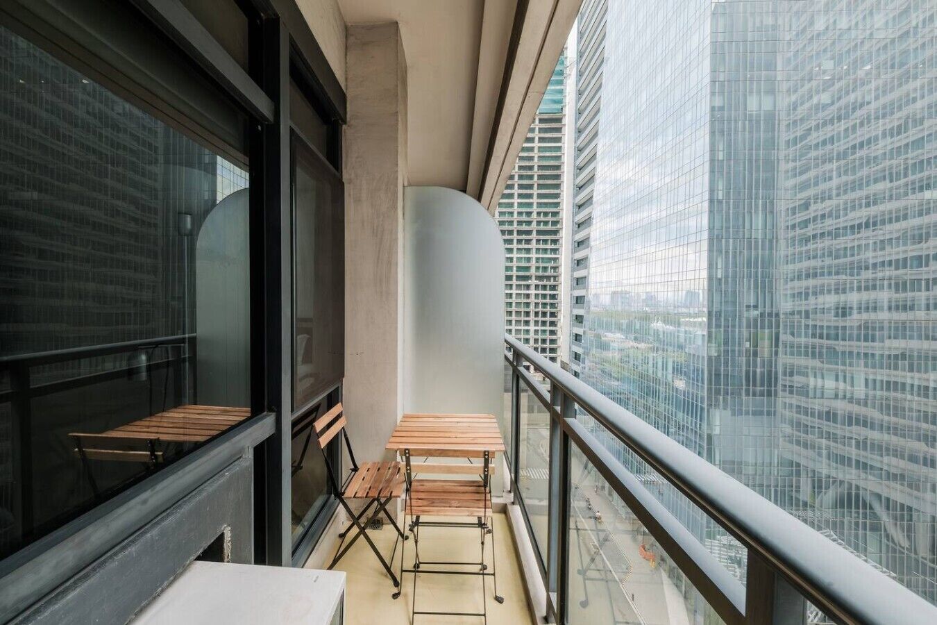 Een balkon met uitzicht op een stadsgezicht, met een tafel en bankjes.