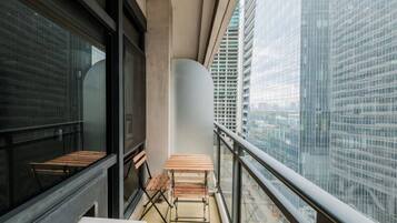 Een balkon met uitzicht op een stadsgezicht, met een tafel en bankjes.