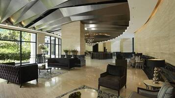 Een ruime lobby met een modern design, met een receptiebalie, zithoeken en grote ramen voor veel daglicht.