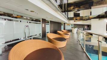 Een moderne lobby met glazen balustrades, rieten zitplaatsen en een zwembad.