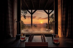 Een kamer met uitzicht op een jacuzzi bij zonsondergang, een schaakbord en twee glazen op tafel.
