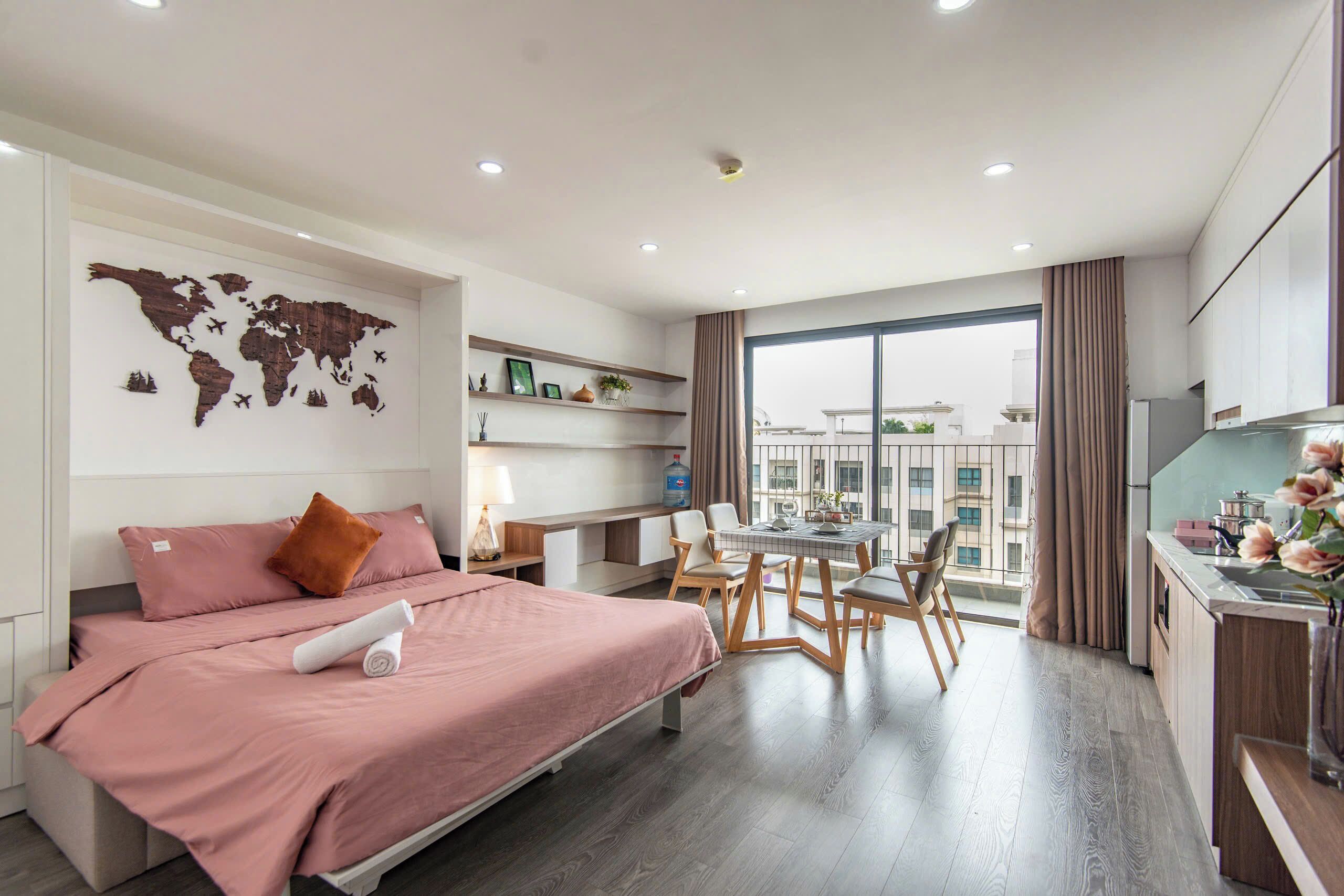 A modern hotel room with a bed, desk, and dining area, featuring a world map on the wall and a large window.