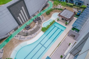 Ein Pool auf dem Dach mit geschwungener Form, umgeben von Liegestühlen und einer kleinen Sonnenterrasse.
