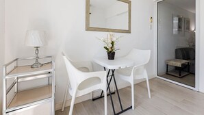 A room with a white chair, a small table with a potted plant, a lamp, and a mirror on the wall. - StayHere 2BR Beach Tropical City Getaway Azure (Parañaque)
