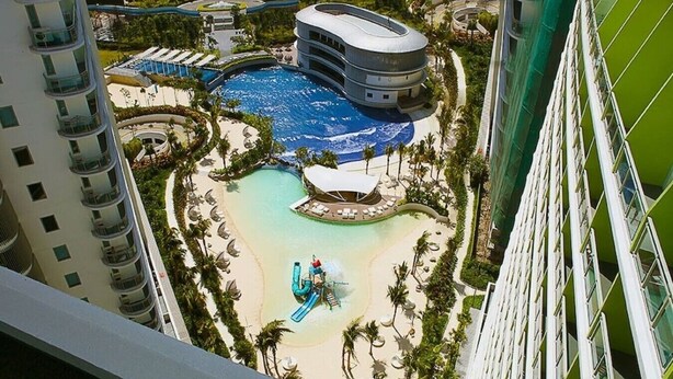 A resort with a pool, beach, and a building with a curved roof. - StayHere 2BR Beach Tropical City Getaway Azure (Parañaque)