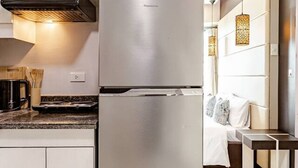 Una cocina moderna con refrigerador de acero inoxidable, armarios blancos y horno integrado.