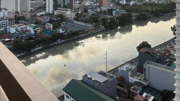 Un paisaje urbano con un río, edificios altos y una combinación de estructuras residenciales y comerciales.