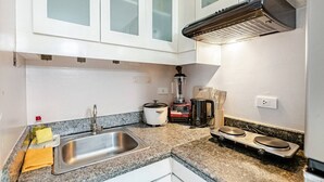 Una cocina con un lavamanos de acero inoxidable, una licuadora, una tetera y un tostador.
