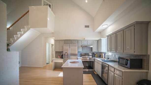 A spacious kitchen with a central island, a dining area, and a staircase leading to an upper level. - A Quiet Lakefront Retreat for Relaxed Getaways (Oak Point)