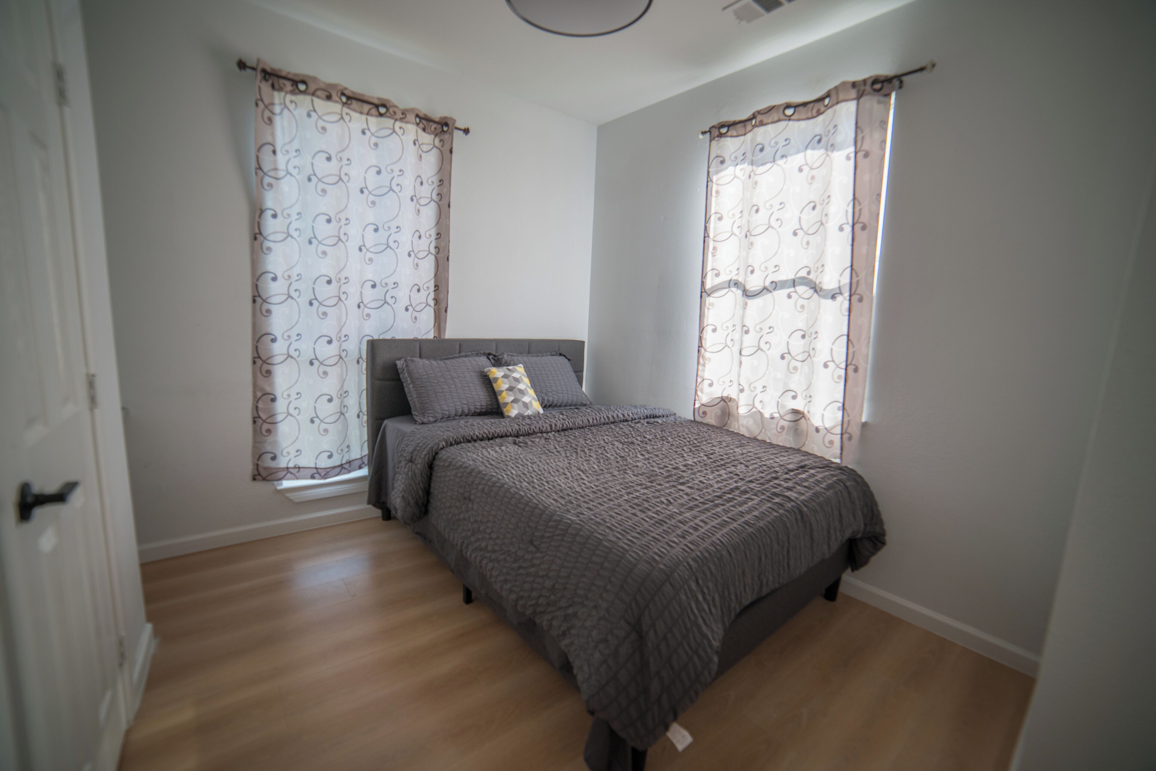 A bedroom with a bed, curtains, and a door.