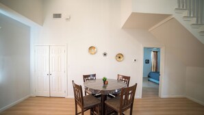 A dining area with a round table, four chairs, and a small plant. There are two doors and a staircase in the background. - A Quiet Lakefront Retreat for Relaxed Getaways (Oak Point)
