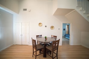 A dining area with a round table, four chairs, and a small plant. There are two doors and a staircase in the background. - A Quiet Lakefront Retreat for Relaxed Getaways (Oak Point)