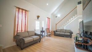 A spacious living room with two sofas, a fireplace, and a staircase leading to an upper level. - A Quiet Lakefront Retreat for Relaxed Getaways (Oak Point)