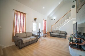 A spacious living room with two sofas, a fireplace, and a staircase leading to an upper level. - A Quiet Lakefront Retreat for Relaxed Getaways (Oak Point)