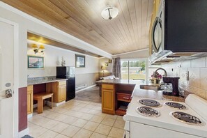 Une cuisine avec des meubles de rangement en bois, une cuisinière et un four à micro-ondes.