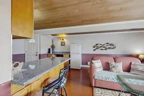 Une cuisine de taille réduite, dotée d’un plan de travail en granit, de meubles en bois et d’un réfrigérateur.