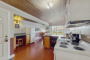 Une cuisine avec des meubles de rangement en bois, une cuisinière et une fenêtre donnant sur un paysage.