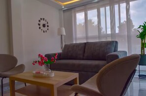 A modern living room with a sofa, a coffee table with a vase of flowers, a lamp, and a wall clock. - Modern and quiet : 2Bdrm. clinic and stadium area (Cali)