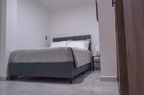 A bedroom with a bed, a nightstand, and a door. - Modern and quiet : 2Bdrm. clinic and stadium area (Cali)
