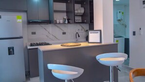 Une cuisine moderne dotée d’un îlot central, de tabourets de bar et d’une pancarte de bienvenue.