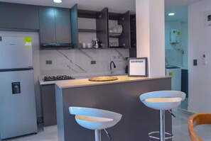 A modern kitchen with a central island, bar stools, and a welcome sign.