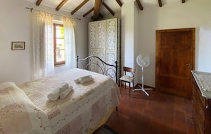 A bedroom with a bed, a chair, a fan, a wardrobe, and a door. - Gorgeous home in Villa Collemandina (Villa Collemandina)