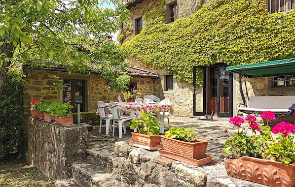 A stone building with a covered patio, outdoor seating, and potted plants. - Gorgeous home in Villa Collemandina (Villa Collemandina)