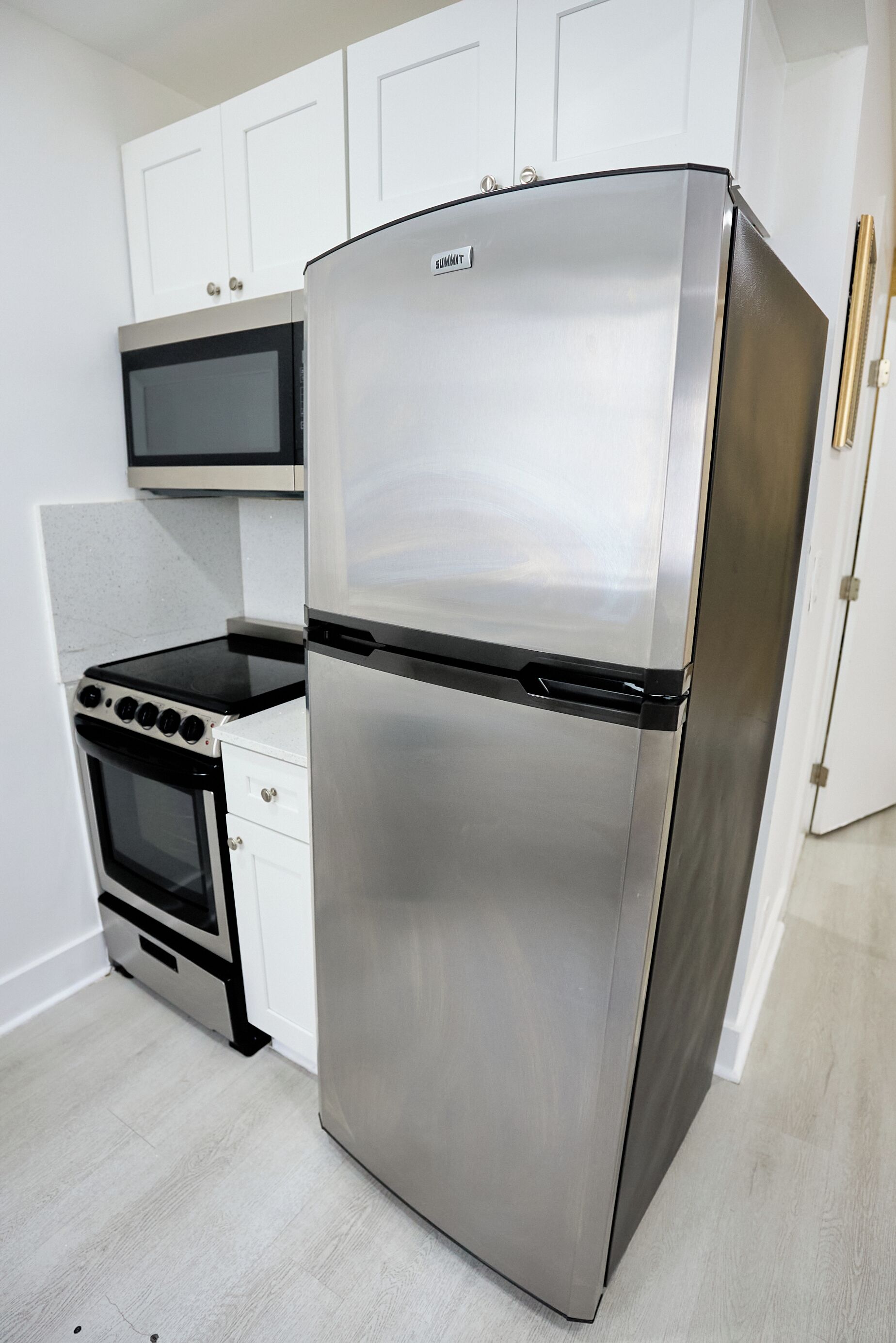 Eine Küche mit einem Edelstahl-Kühlschrank, einer Mikrowelle und einem Herd.