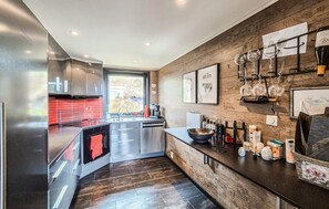 Et moderne køkken med røde backsplash, rustfrie stålemmer og en trævæg.
