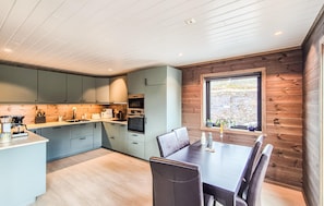 A modern kitchen with light blue cabinets, a dining table with chairs, and a window with a view of the outdoors.