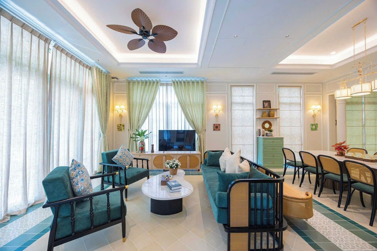 A spacious living room with a large ceiling fan, a television, and a dining area with chairs and a table.