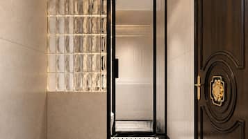 A hallway with a patterned floor, a wall with a light fixture, and a door with a decorative handle.