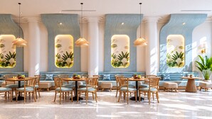 Een ruime hotellobby met zithoeken, houten stoelen en tafels.