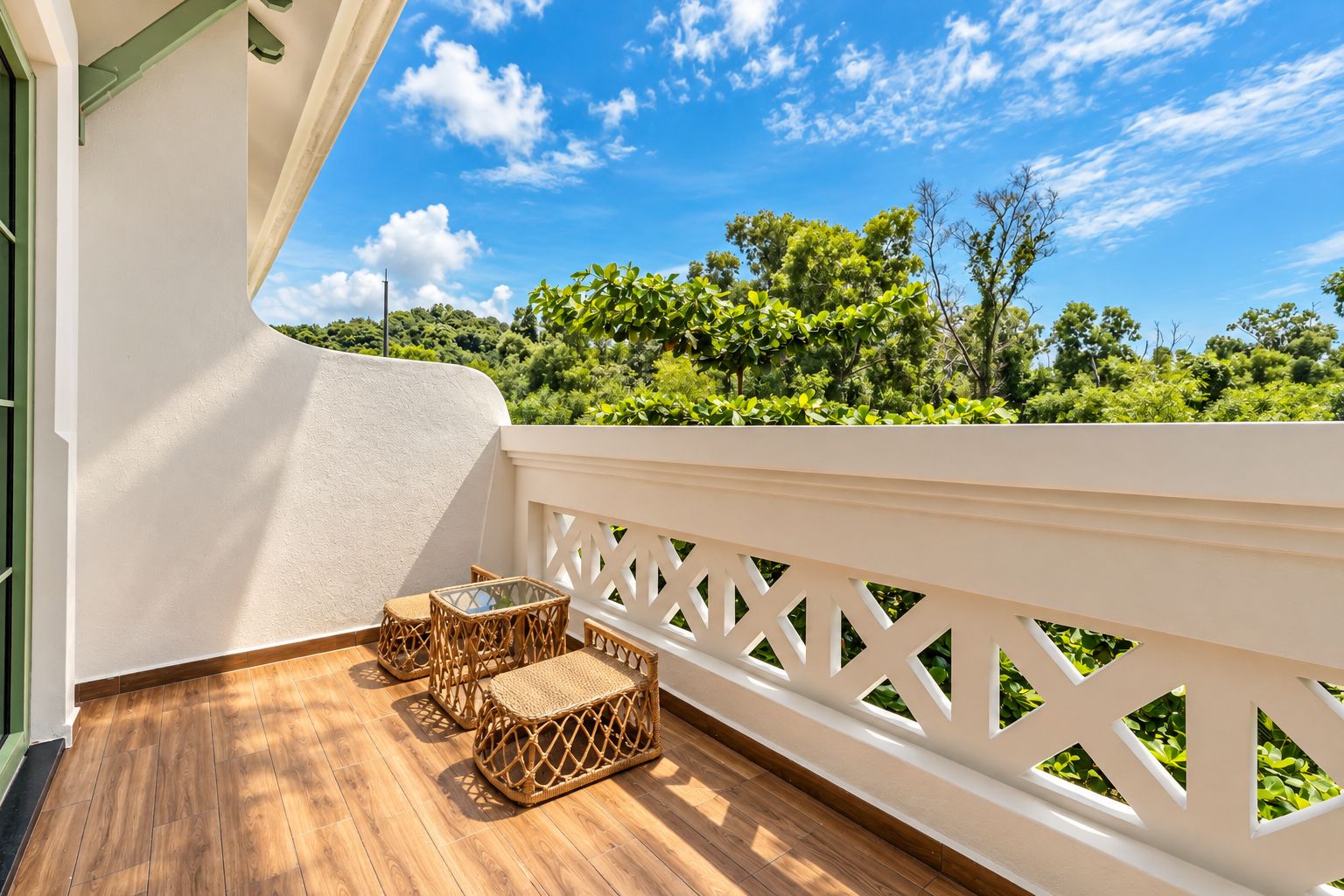 A balcony with a wooden floor, white railing, and wicker furniture.