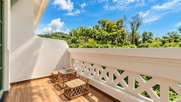 A balcony with a wooden floor, white railing, and wicker furniture.