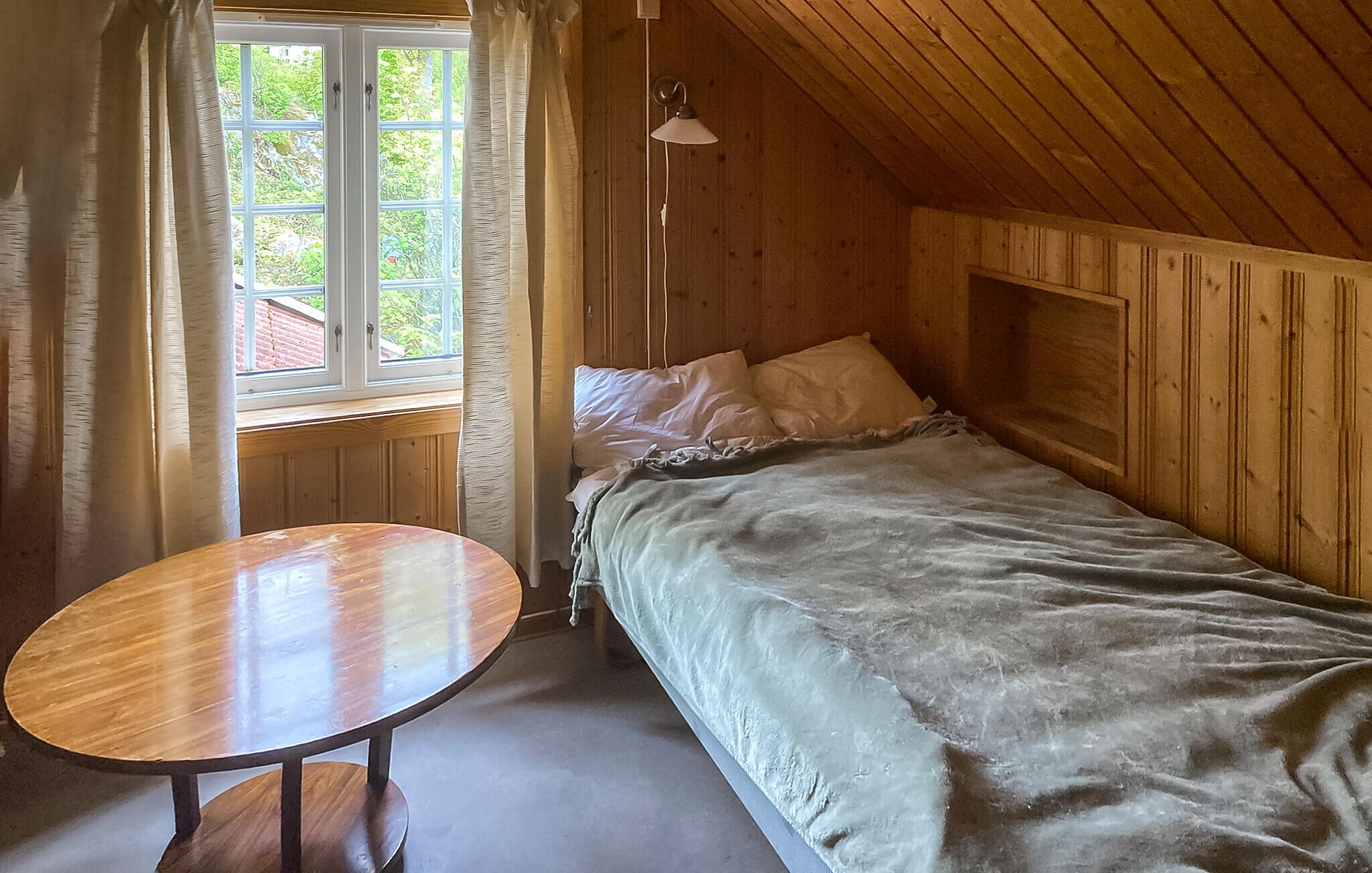 Een kamer met houten vloeren, een bed, een tafel en een raam.