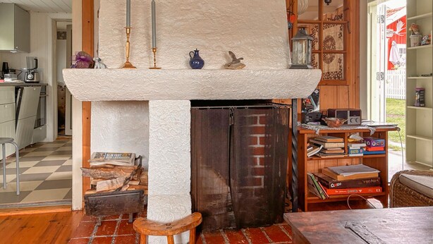 Una habitación con chimenea, una mesa de madera, una estantería y suelo a cuadros.